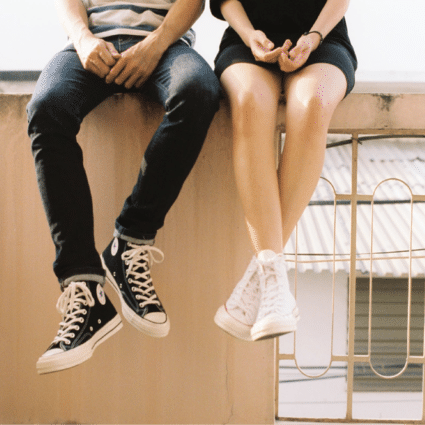 Young couple sitting on an edge wearing converse shoes