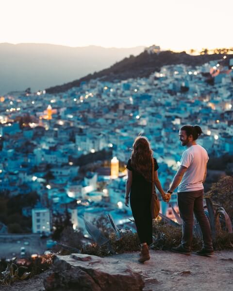 Couple standing on cliff top viewing cityscape