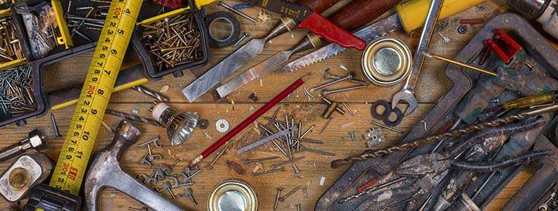 assortment of tools, screws, and nails on workbench