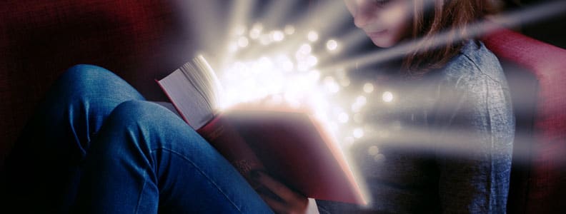 girl reading from book with magical lights emitting from book